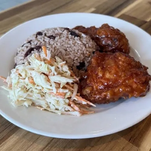 BBQ-glazed fried chicken served with rice and peas and coleslaw