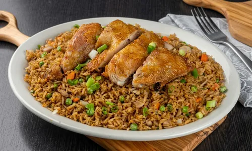 Fried rice with peas and carrots, topped with sliced roast chicken